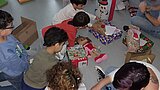 Sternschnuppenaktion 2025 KiTa Kinder sitzen mit ausgepackten Geschenken auf dem Boden