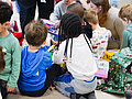 Sternschnuppenaktion 2025 Kinder sitzen mit dem Rücken zur Kamera auf dem Boden und packen Geschenke aus