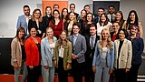 Die Graduierten stehen auf einer Bühne. Hinter ihnen ist das Logo der HSPV NRW zu sehen.