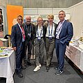 Europäischer Polizeikongress 2026 Fünf Menschen stehen eng nebeneinander vor einem Messestand zwischen zwei Tischen.