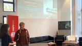 Zwei Frauen stehen im Senatssaal, im Hintergrund ist die PowerPoint-Präsentation der Veranstaltung zu sehen.