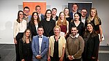 Die Graduierten stehen auf einer Bühne. Hinter ihnen ist das Logo der HSPV NRW zu sehen.