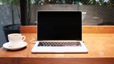Ein Laptop und eine Kaffeetasse stehen auf einem Schreibtisch.