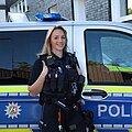 Europäischer Polizeikongress 2026 Eine Polizistin steht in Uniform vor einem Streifenwagen und hat die Hände in den Brusttaschen.